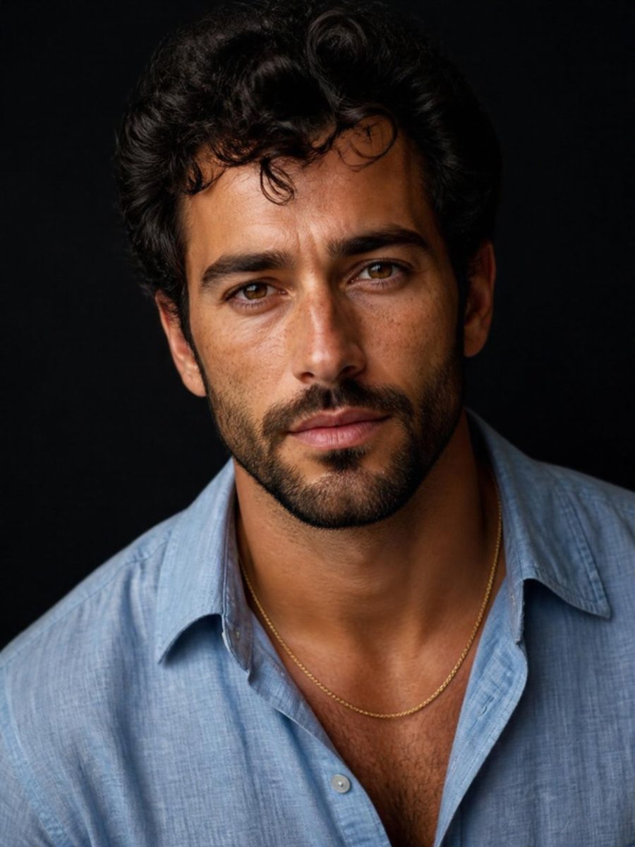 Man with dark curly hair and a short beard in a pale blue linen shirt